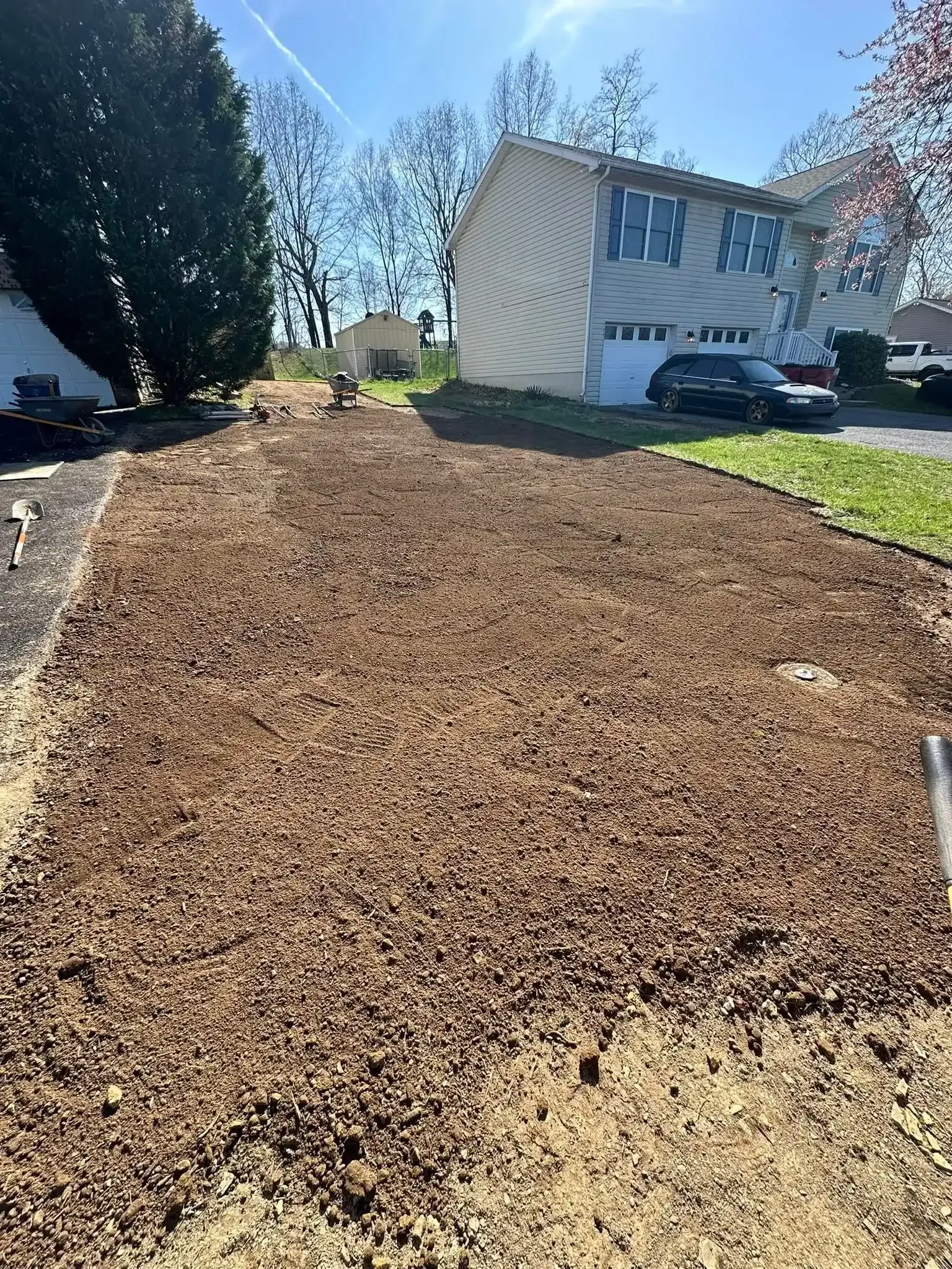 Freshly mulched front yard with a house, cars, and trees in bright sunlight