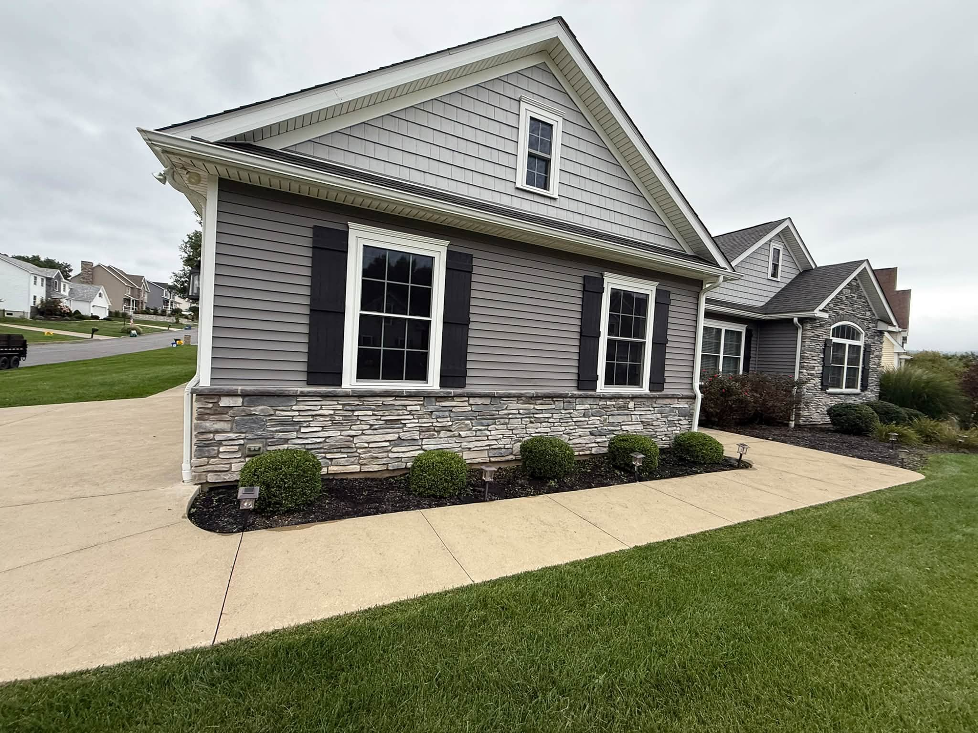 Gray suburban house with stone facade, white trim, and a small front lawn and driveway
