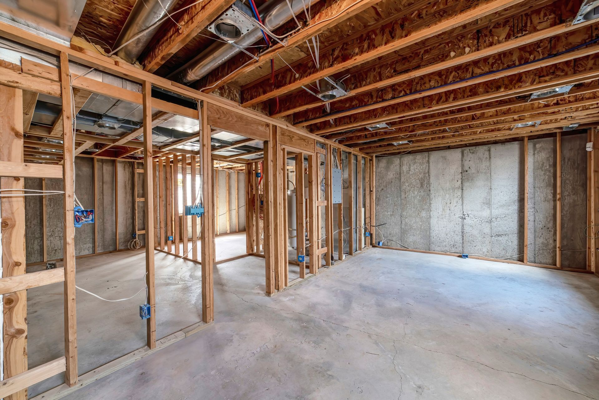 Unfinished basement with wooden framing, concrete floor, and exposed ceiling.