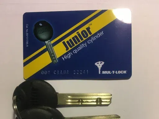 A Mul-T-Lock Junior key card with a unique serial number placed above two dimple keys on a white background.