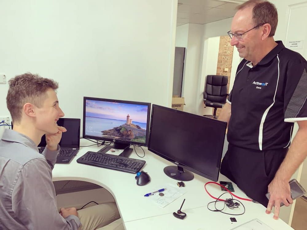Two Men Are Standing Next To Each Other In Front Of A Computer Desk  — ActiveCo.IT in Taree, NSW