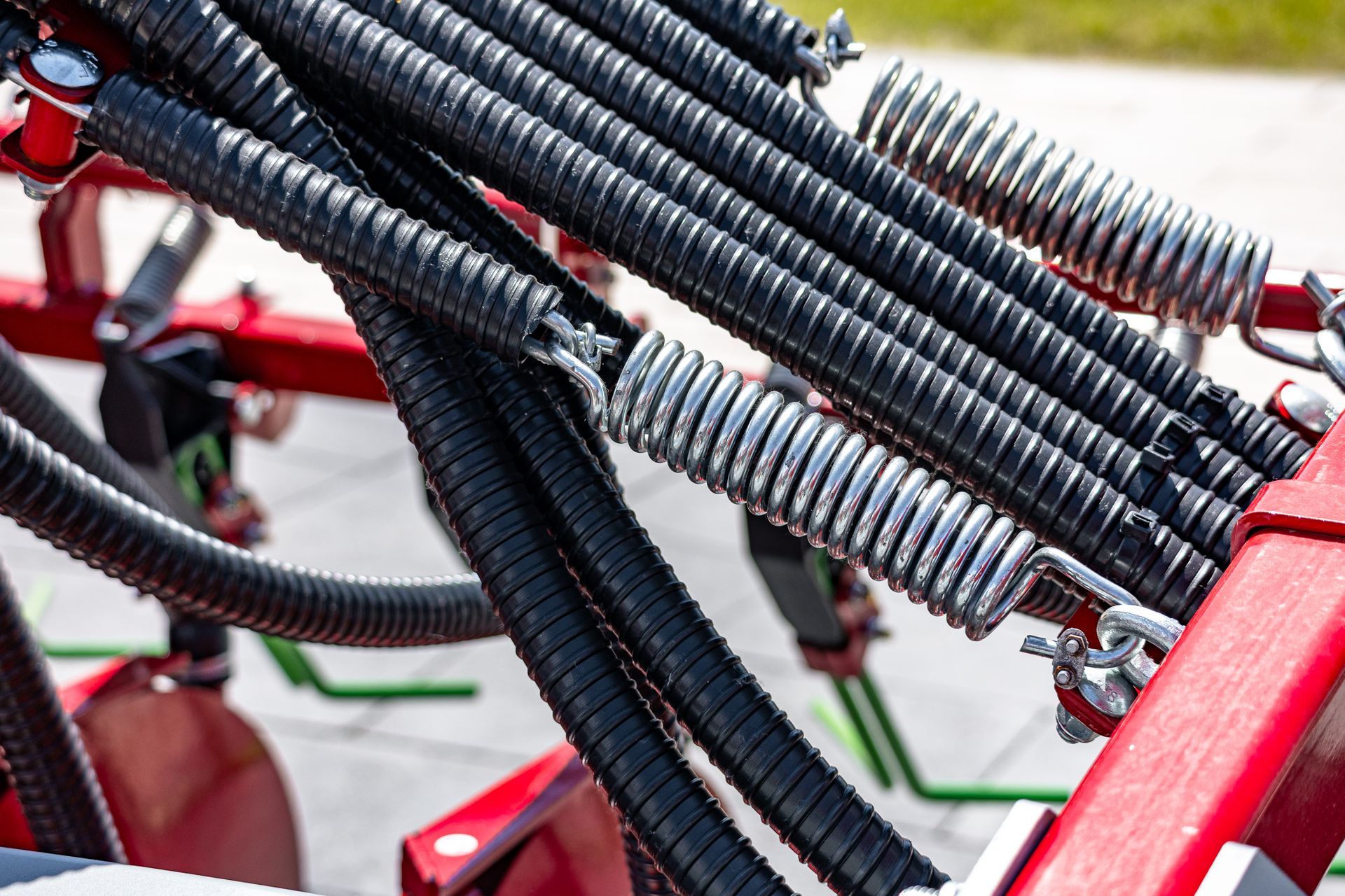 Extension springs connecting hydraulic hoses on red agricultural equipment.