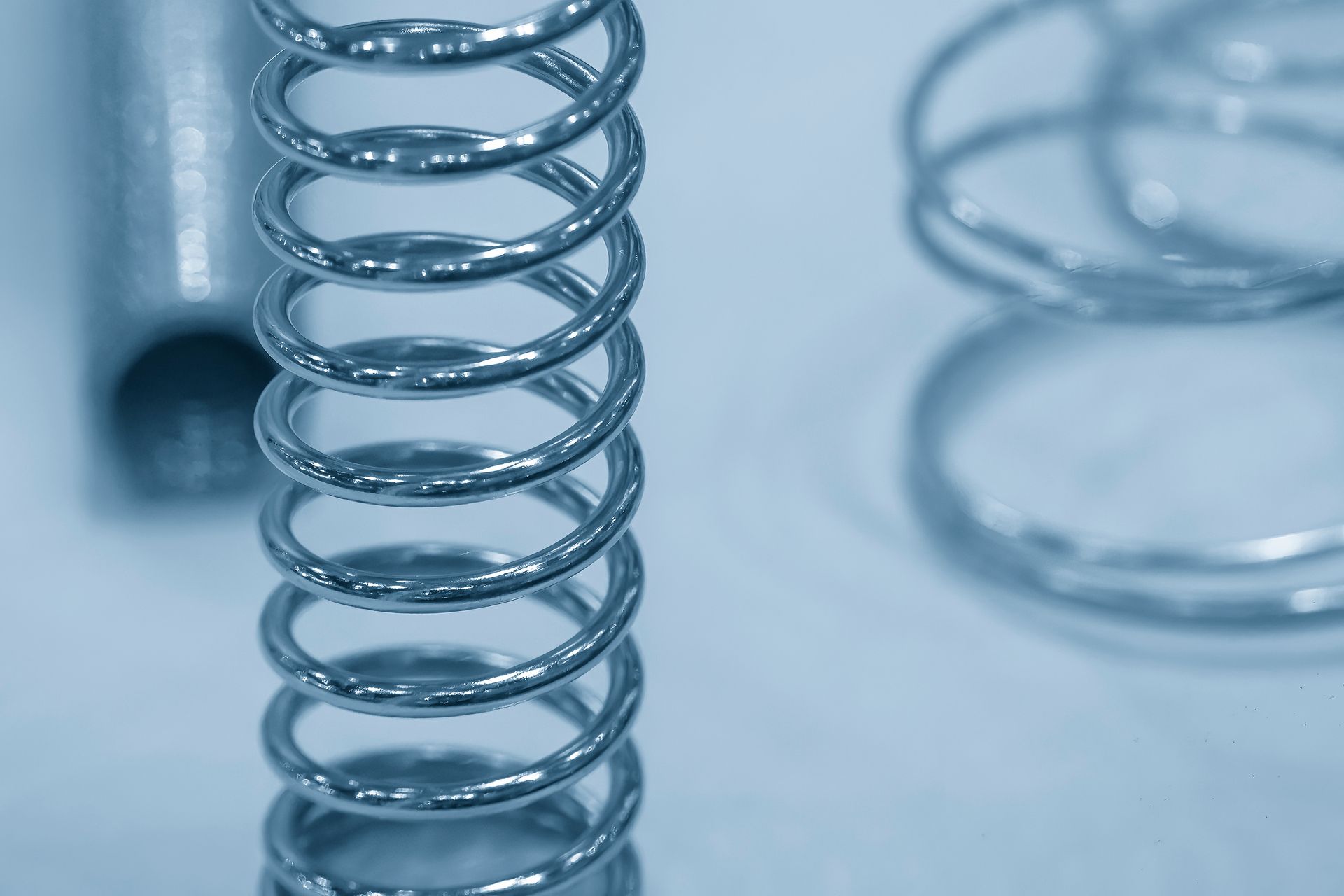 Close-up of industrial parts by compression spring supplier on light blue surface. Close-up of industrial parts by compression spring supplier on light blue surface.