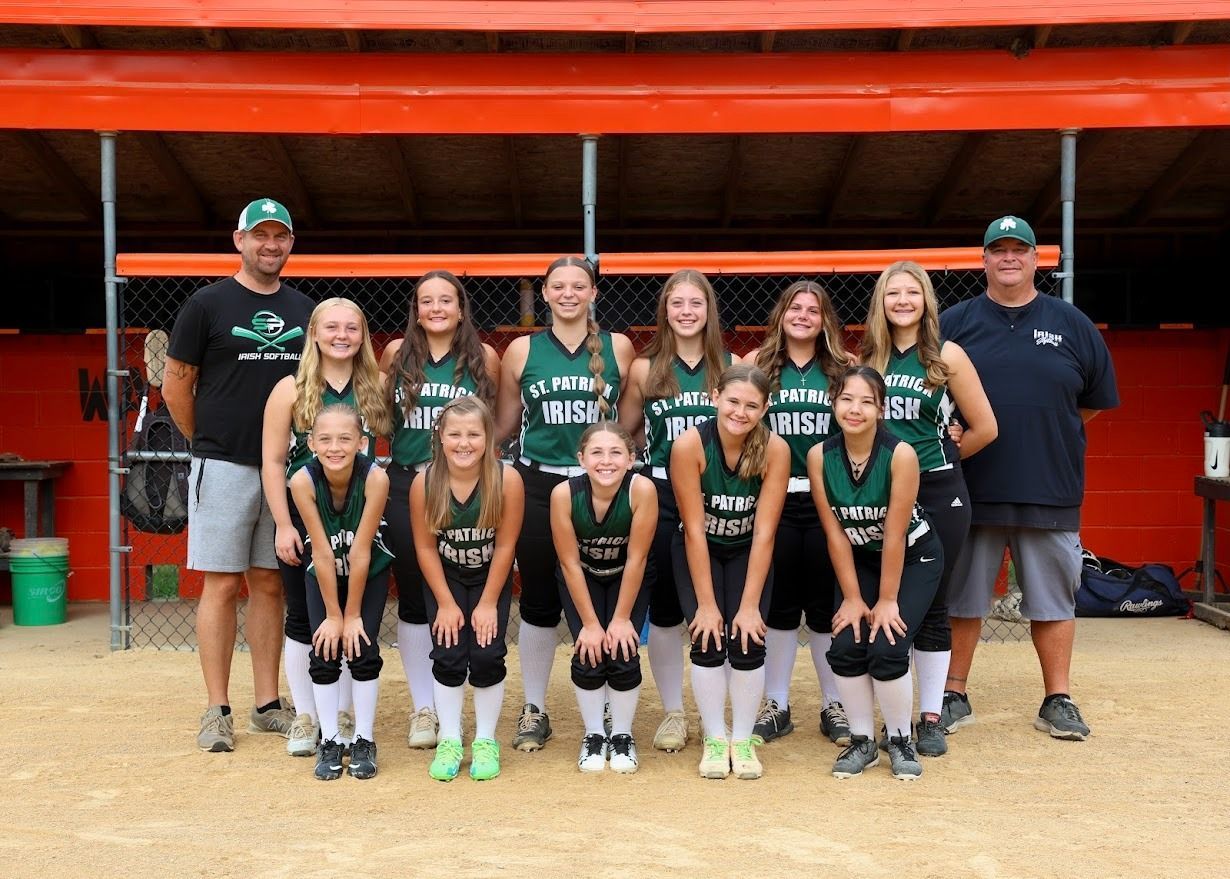 Softball team posing, green and black uniforms, under a red roof.