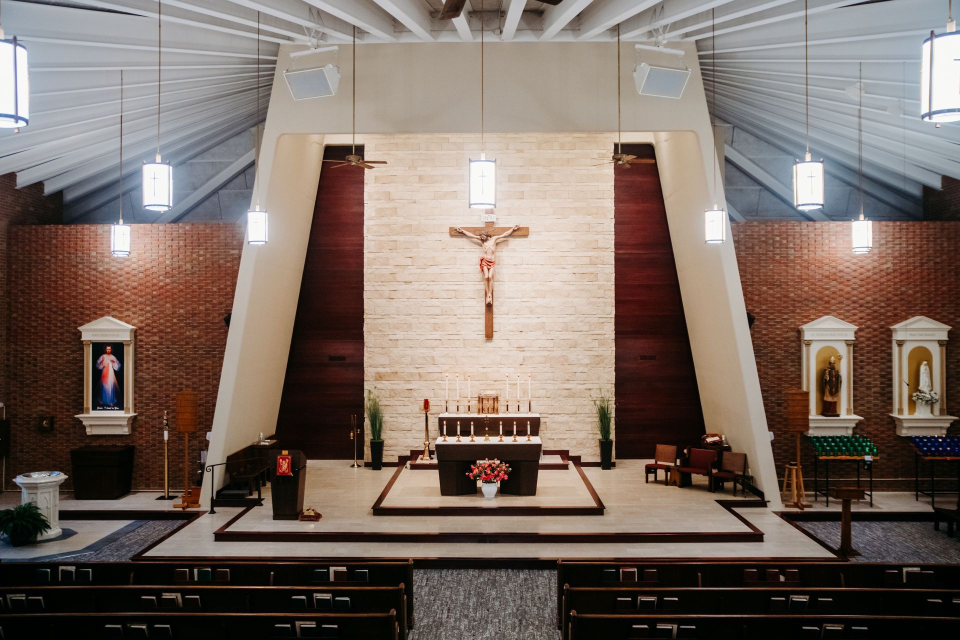 Interior church view with crucifix over altar, surrounded by brick walls and pews.