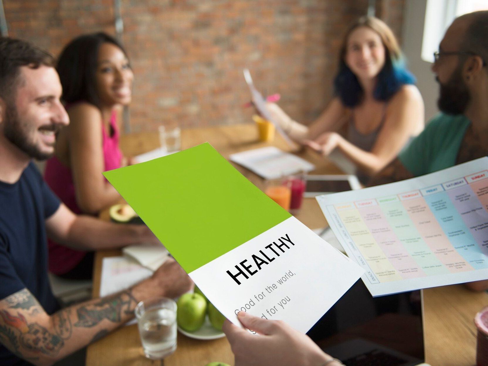 Group of people discussing healthy eating, holding a green flyer that reads