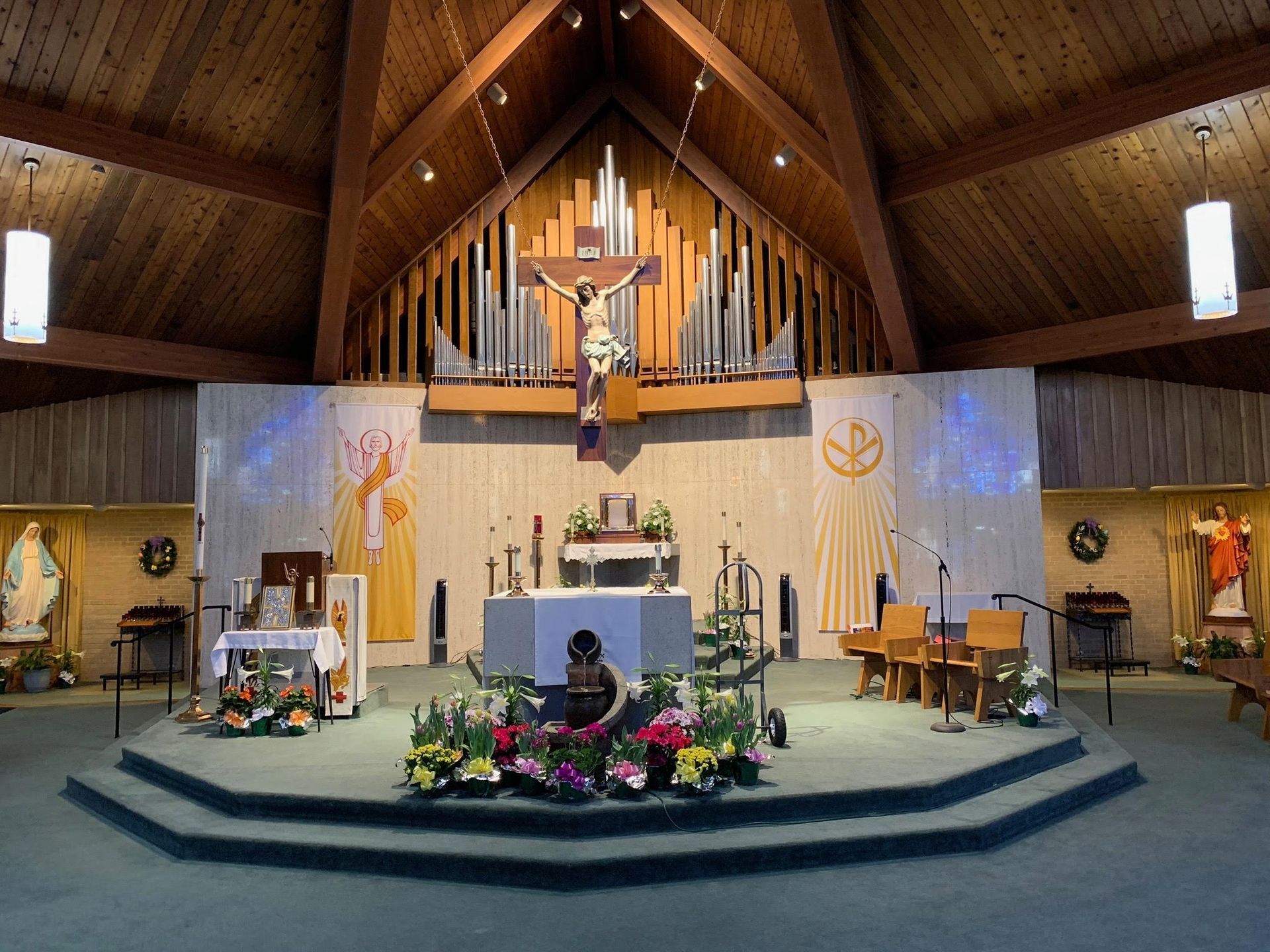 Interior of a church. Altar with crucifix, organ pipes, stained glass and floral decorations.