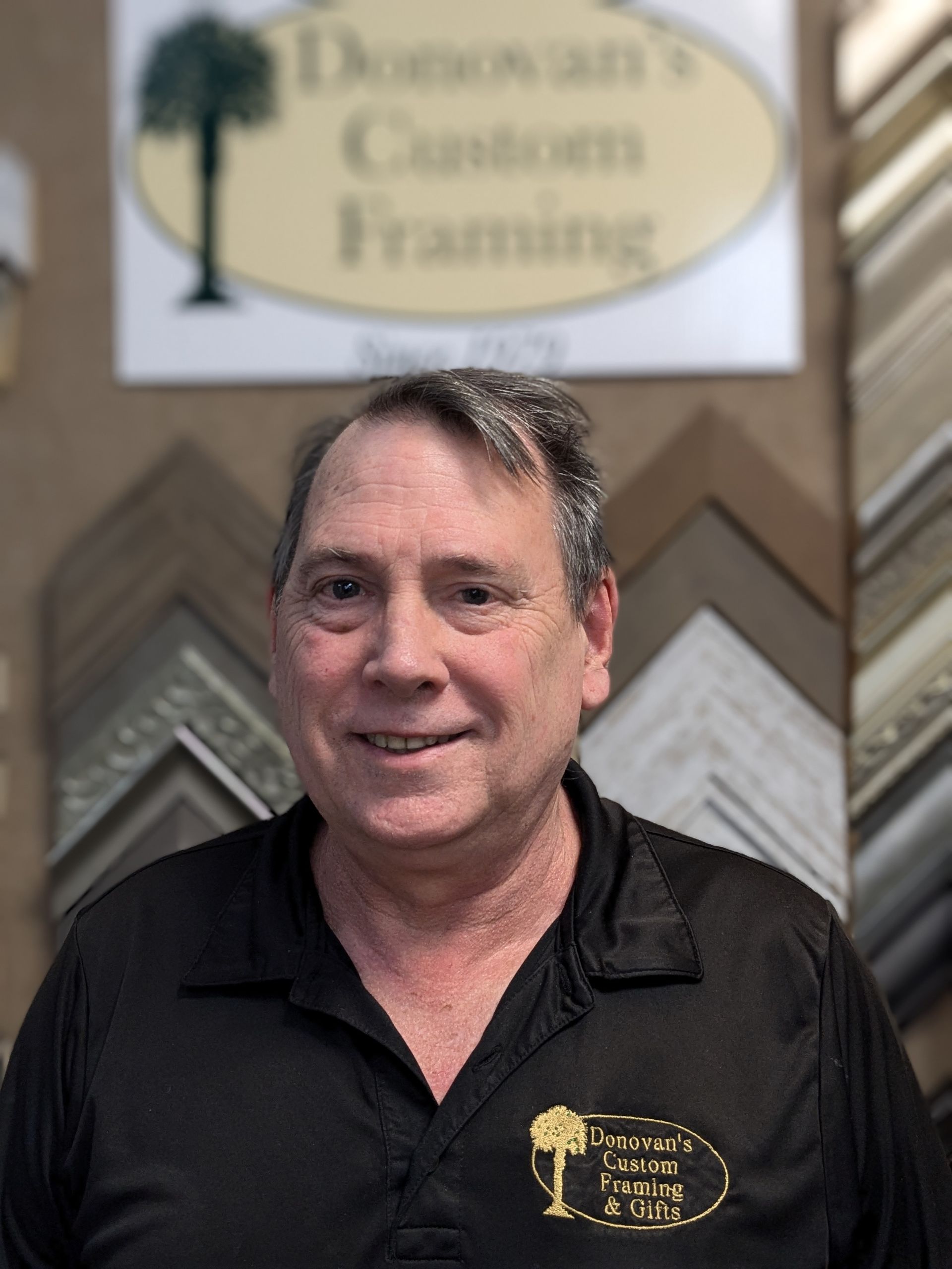 Man in black shirt smiles in front of 