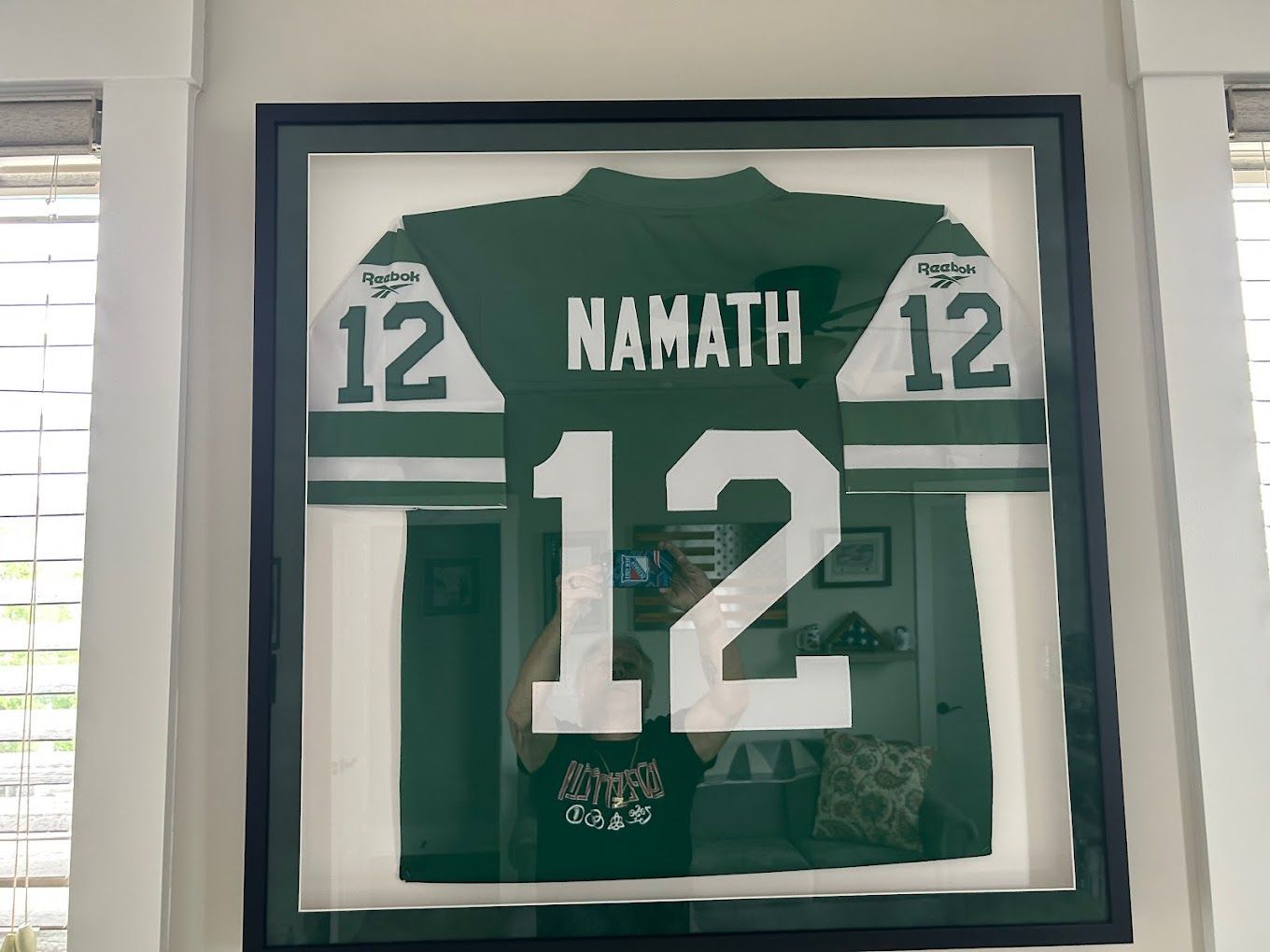 Framed New York Jets Joe Namath jersey (green/white) with number 12, displayed on a wall.