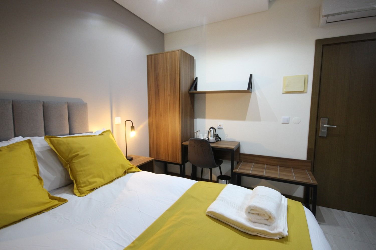 Bedroom with bed, desk, and wardrobe; white and yellow color scheme.