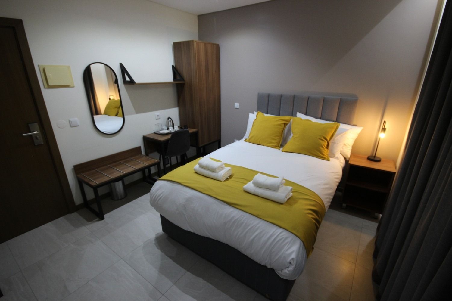 Cozy hotel bedroom with a double bed, yellow accents, and a desk.