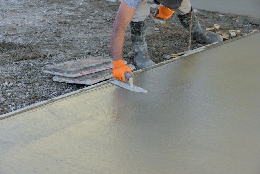 Worker smoothing wet concrete with a trowel on a construction site