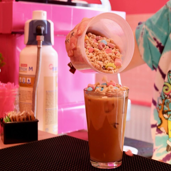 A person is holding a cup of pink slime with hearts on it.