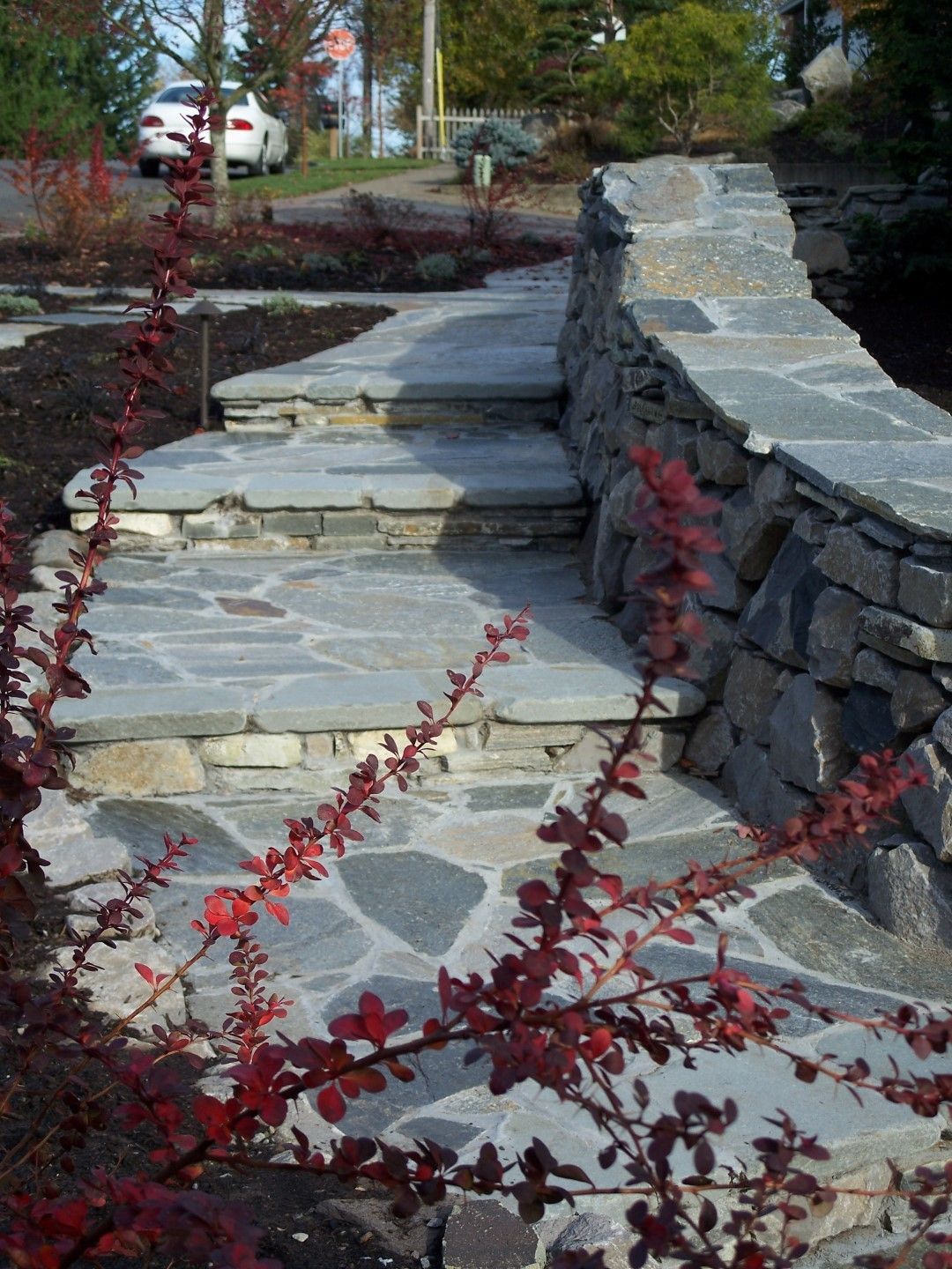 A stone walkway with a car parked in the background