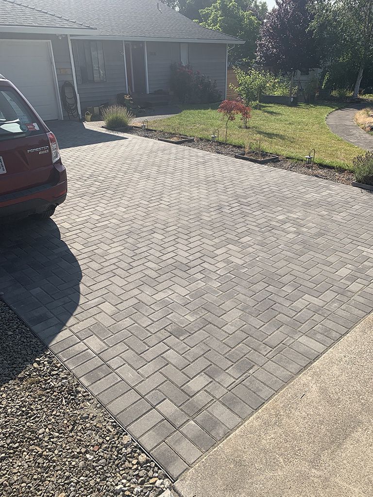A car is parked in a driveway next to a house.