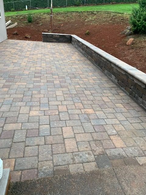 A brick patio with a stone wall surrounding it