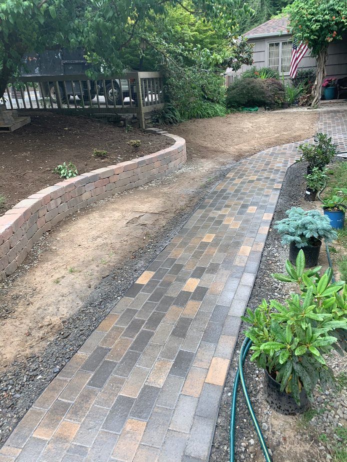 A brick walkway leading to a house with a hose attached to it.