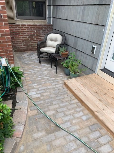 A patio with a chair , table and potted plants.