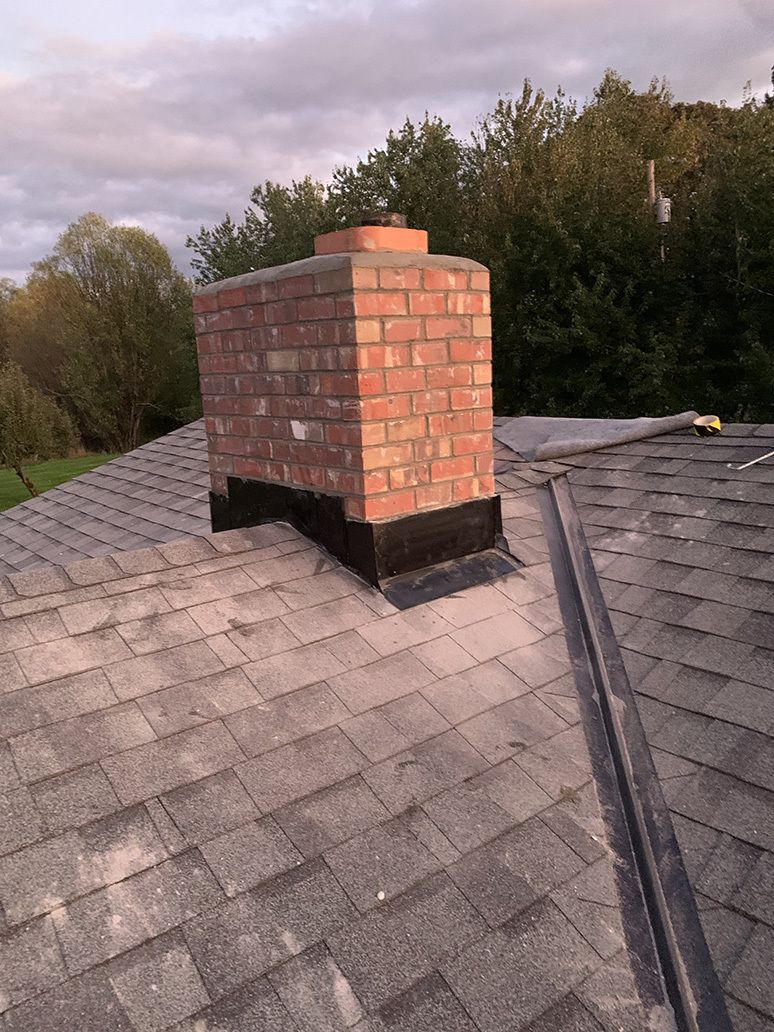 A brick chimney is sitting on top of a roof.