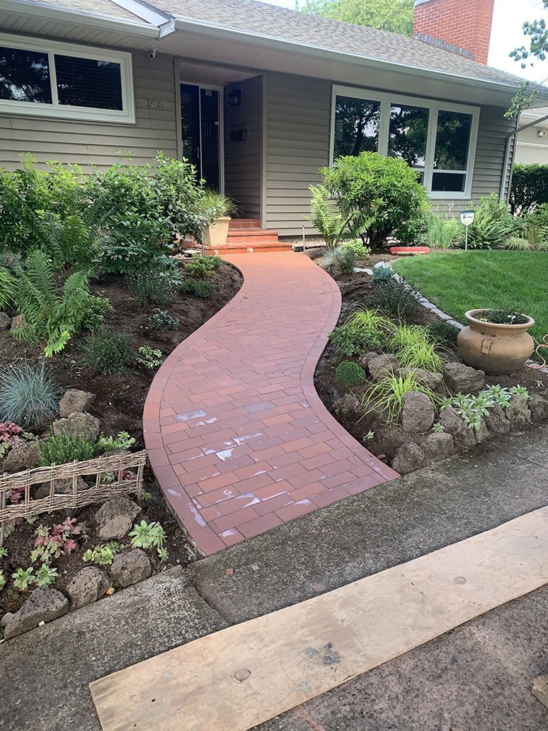 A red brick walkway leading to the front of a house.