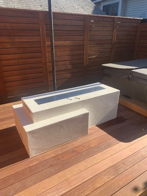 A wooden deck with a fire pit and a wooden fence in the background.