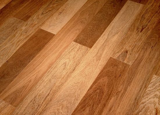 A close-up of hardwood flooring featuring varying shades of brown planks with a natural wood grain texture.