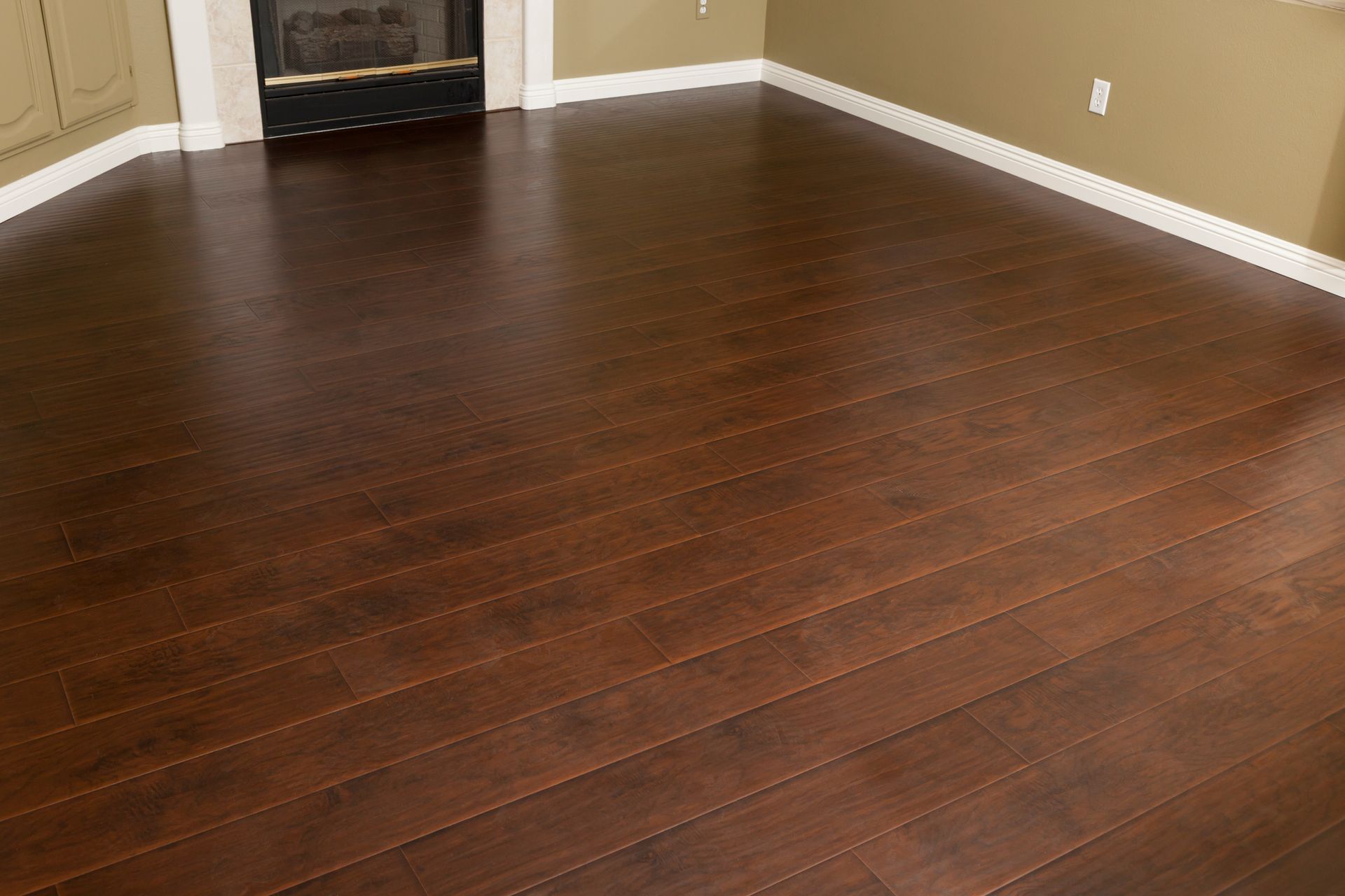 Dark brown hardwood flooring in a room with white baseboards and a fireplace.