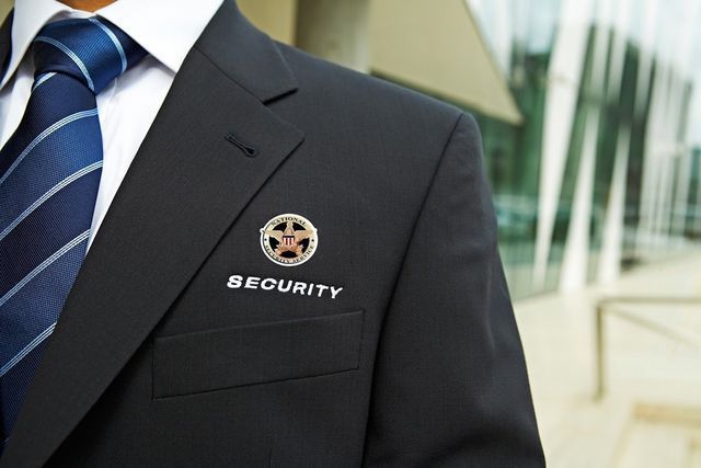 A man in a suit and tie has a security pin in his pocket