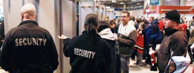 Two security guards standing in front of a crowd of people