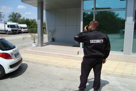 A security guard is standing in front of a building taking a picture