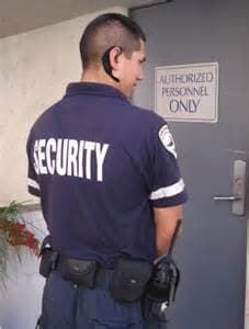 A security guard is standing in front of a door.