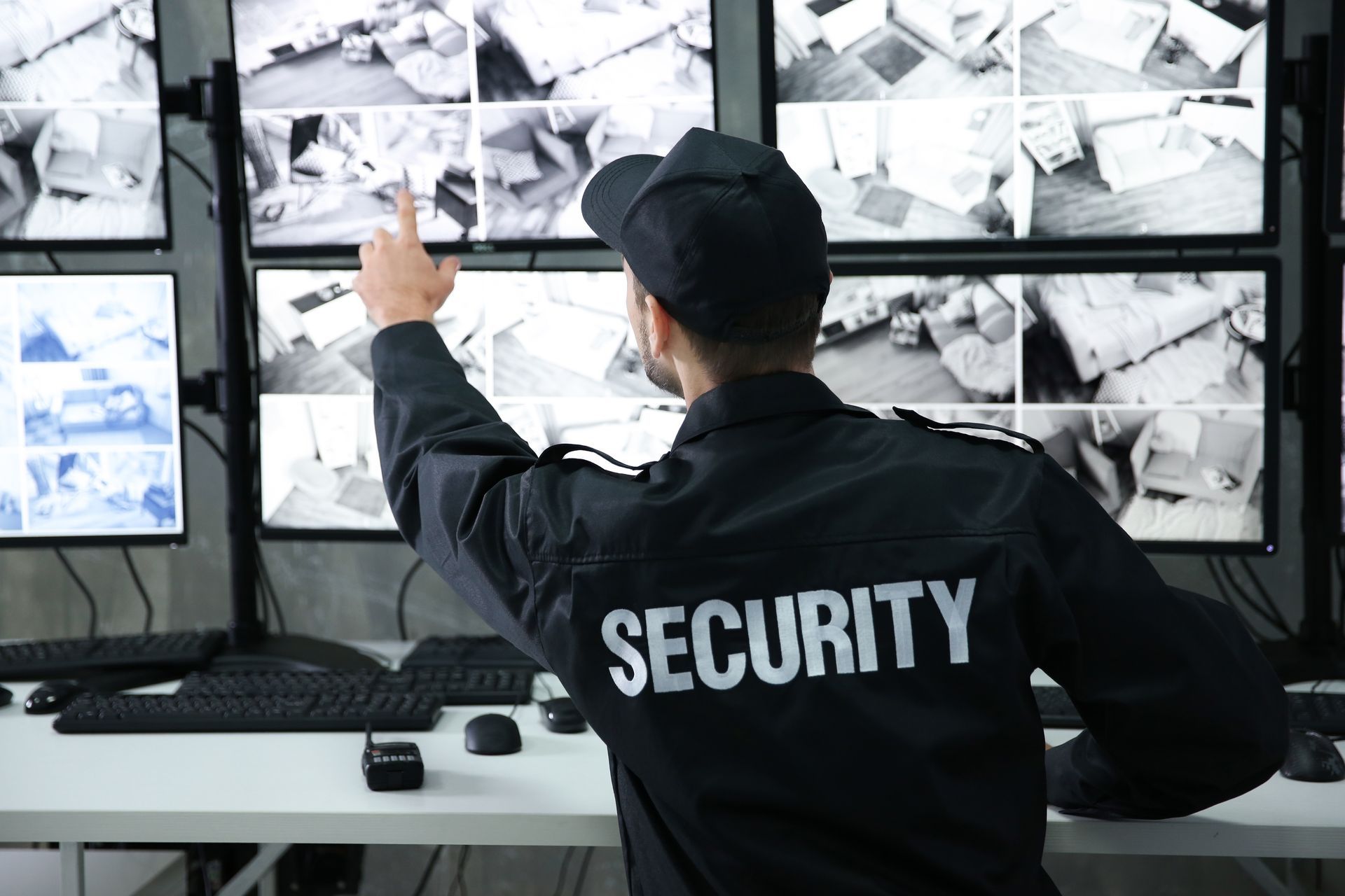 Security guard monitoring multiple CCTV screens in a surveillance control room.