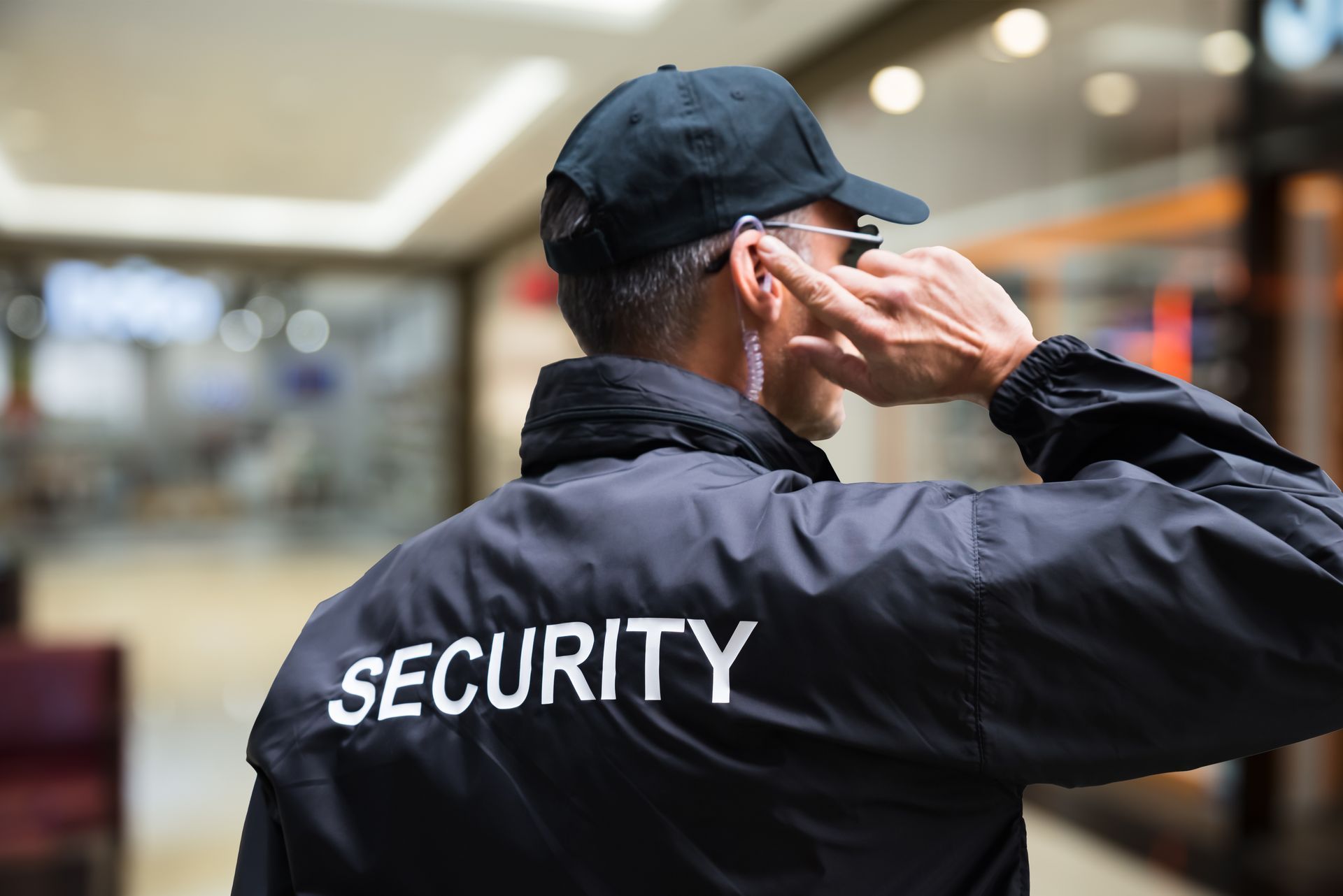 Uniformed security guard with earpiece monitoring a retail property Uniformed security guard with earpiece monitoring a retail property