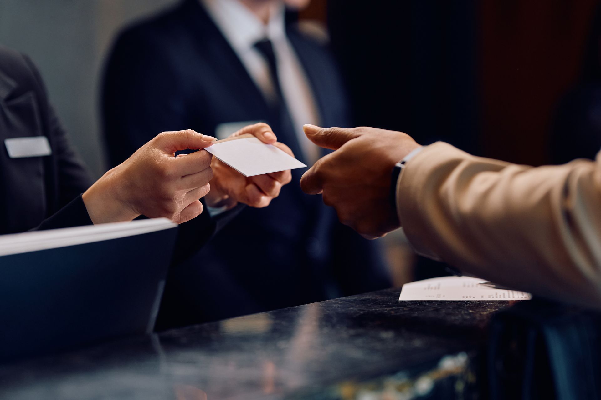 Close up of hotel receptionist giving room cardkey to hotel guest.