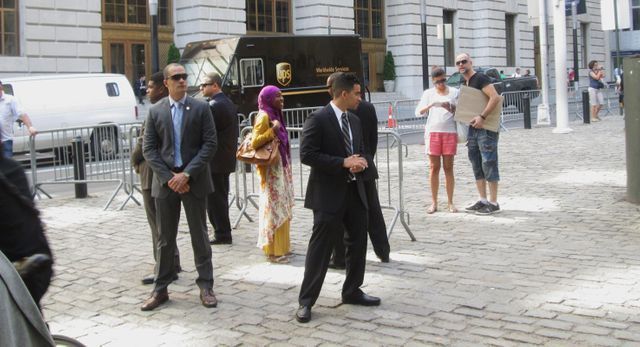 A group of people are standing on a cobblestone street.