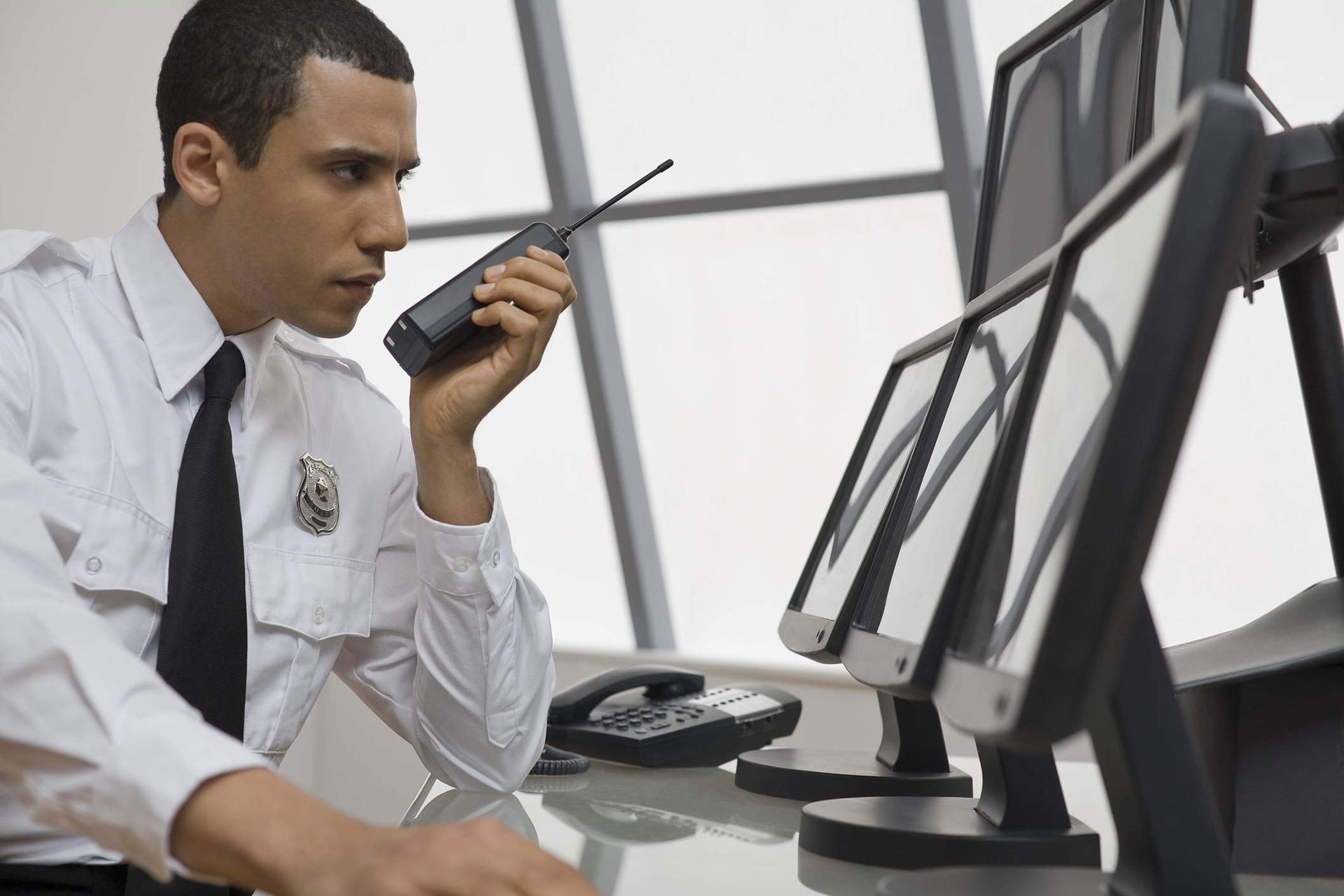 Front desk security guard monitoring building safety with multiple computer screens.