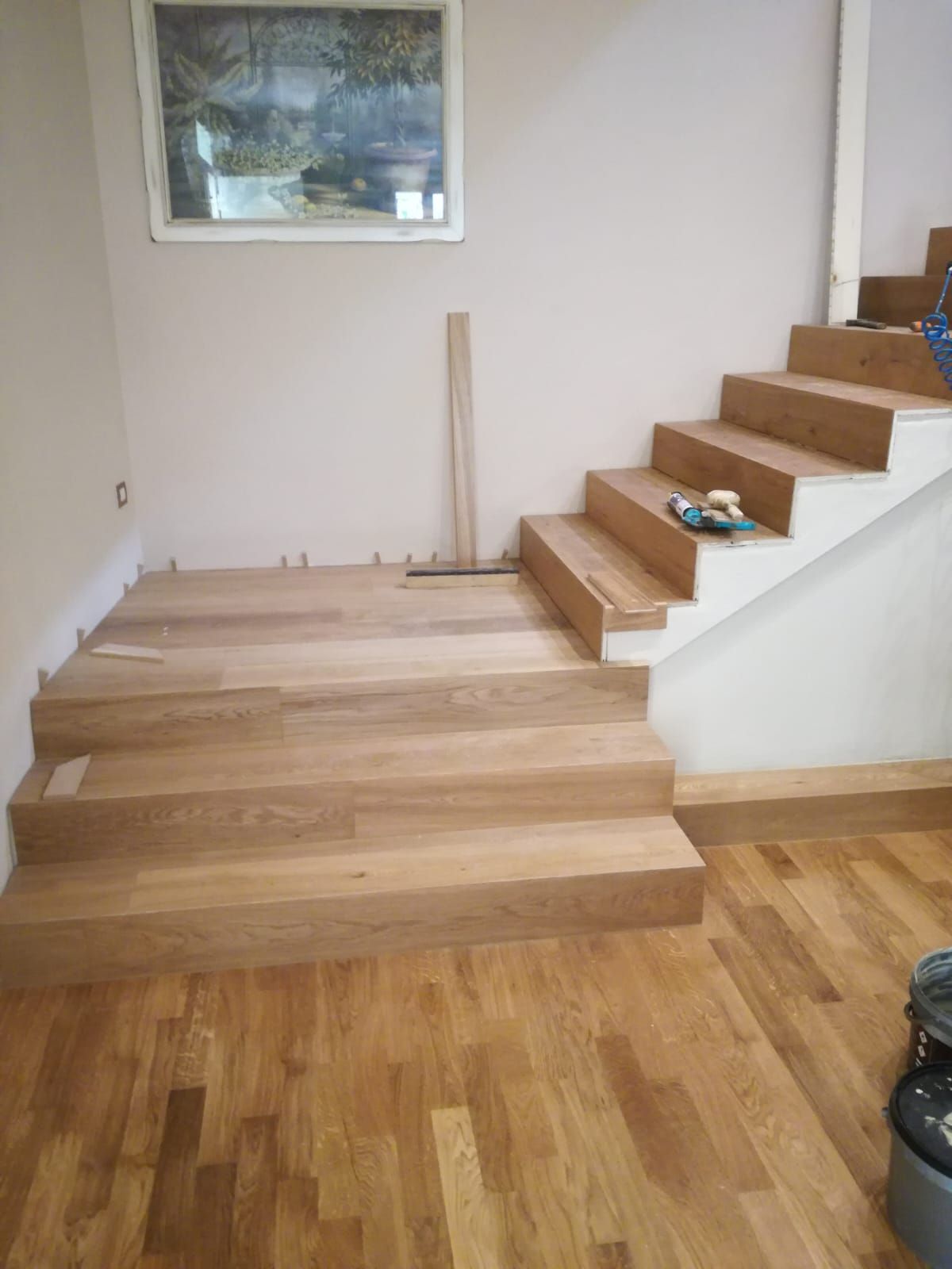 Scala in costruzione con nuovi gradini in legno e pareti laterali bianche in un piccolo pianerottolo interno
