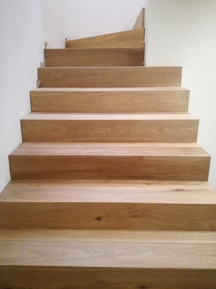 Scala in legno con gradini marrone chiaro e pareti bianche