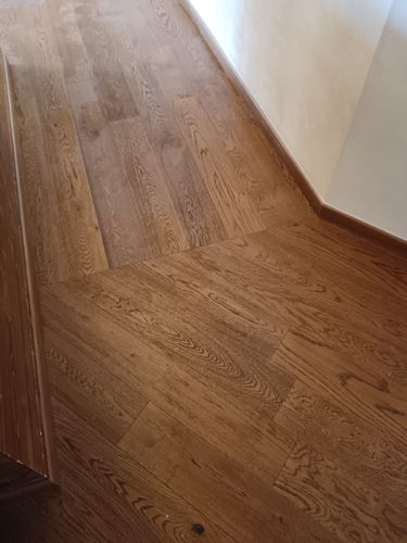 Pianerottolo di una scala in legno con pavimento in parquet marrone e pareti beige