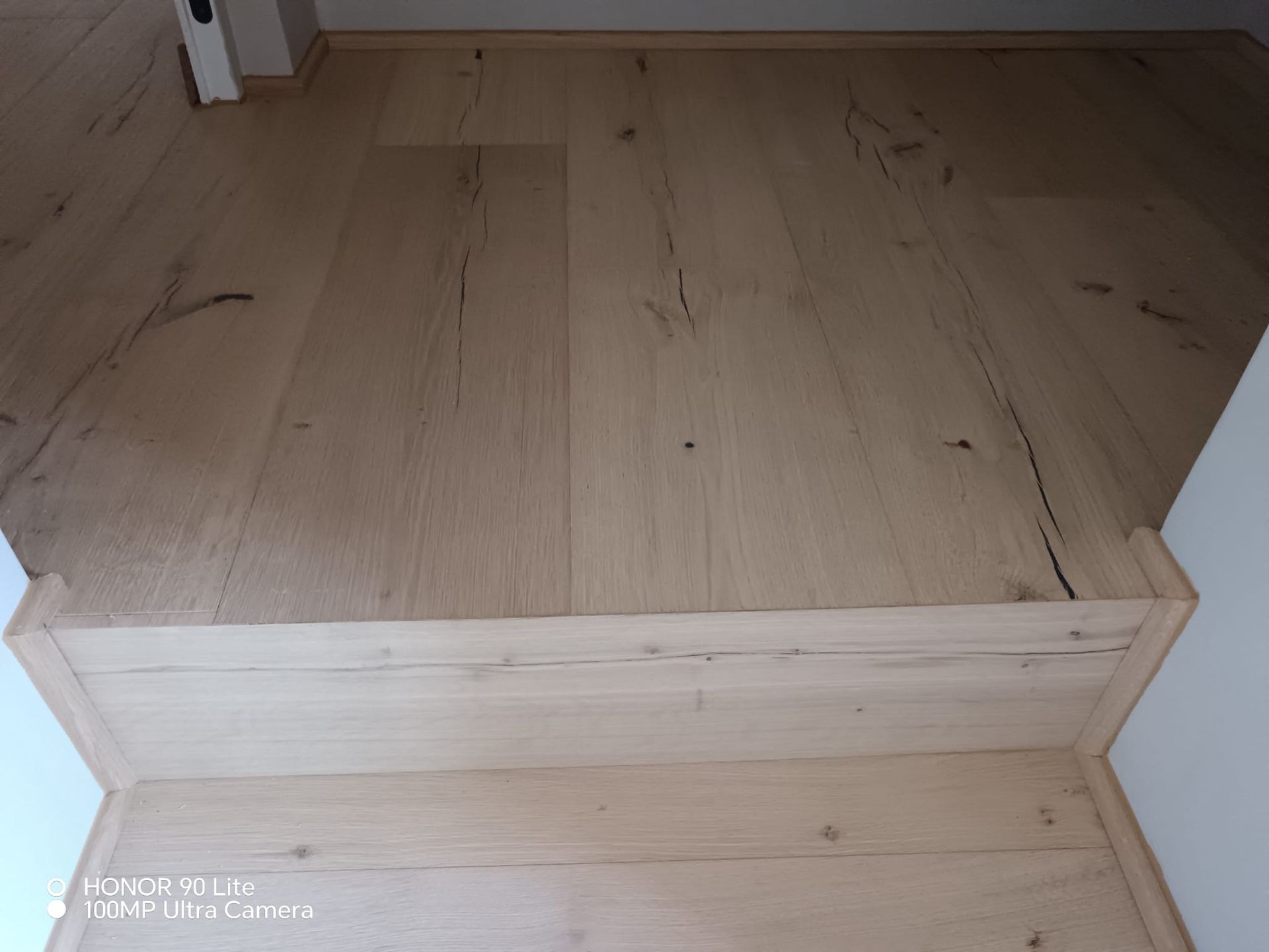 Gradino in legno che conduce a un pavimento in legno chiaro in una stanza vuota