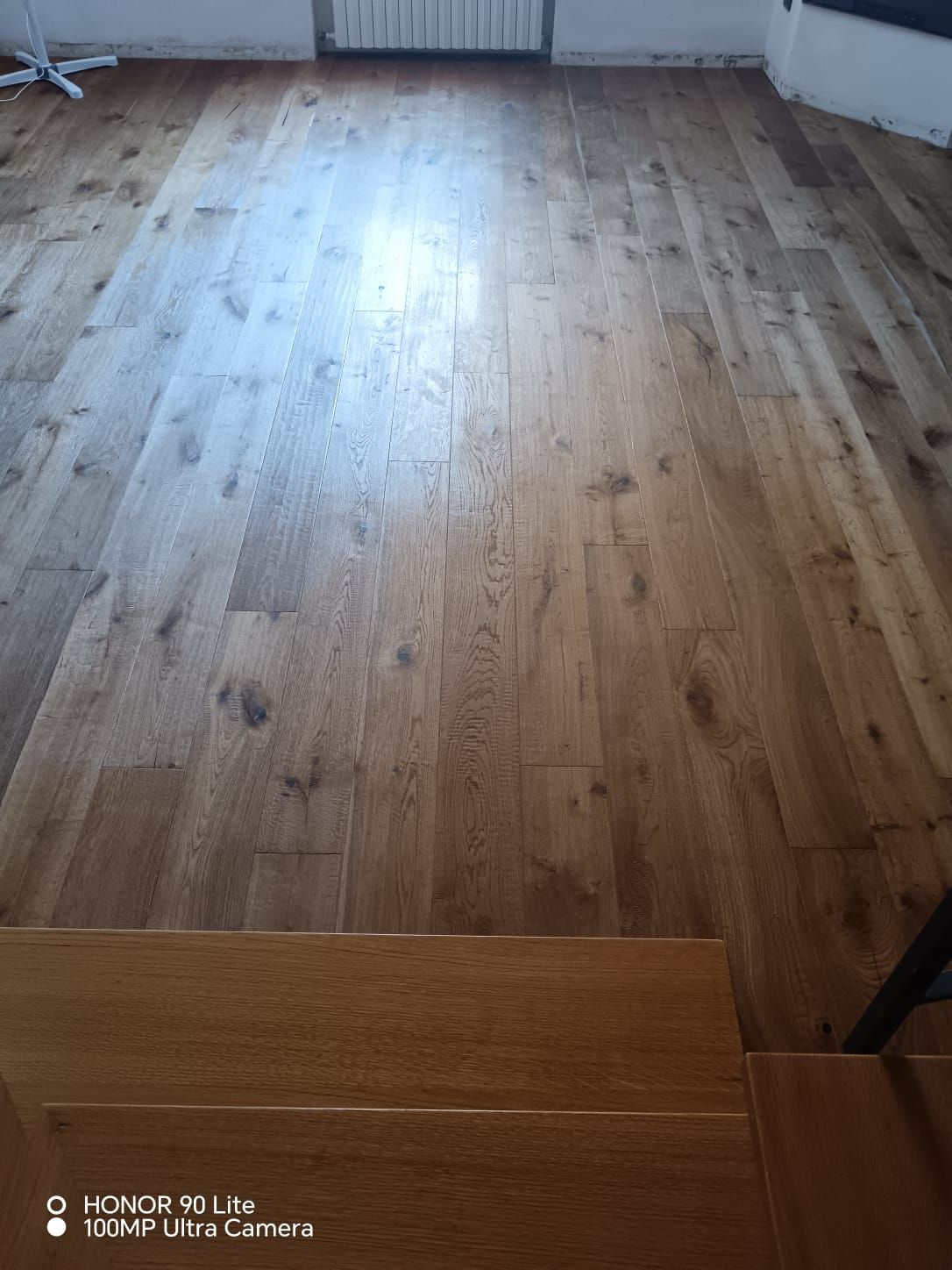 Pavimento in legno vuoto in una stanza illuminata dalla luce delle finestre, con un piccolo gradino in fondo.