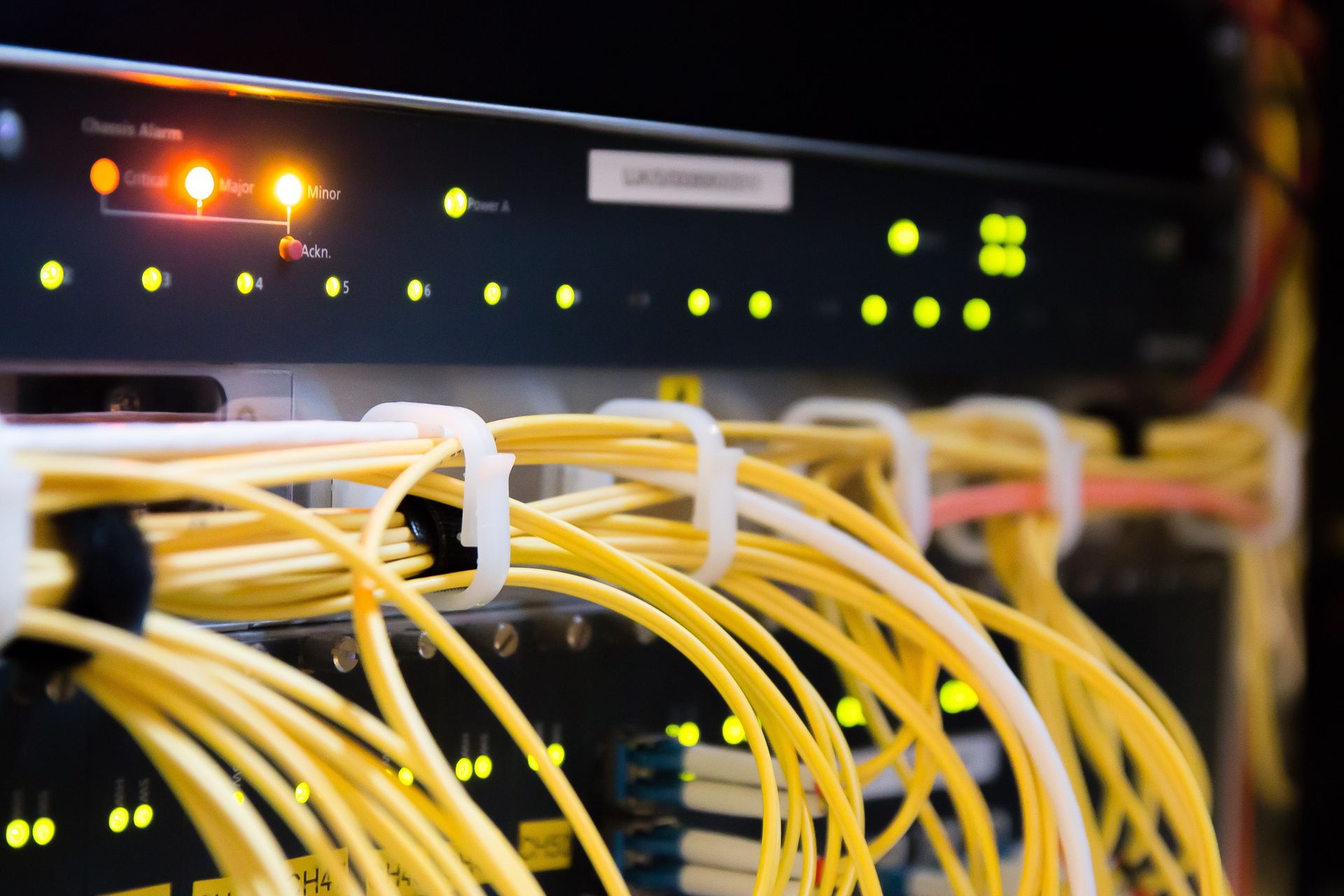 A bunch of yellow wires are connected to a server in a server room.