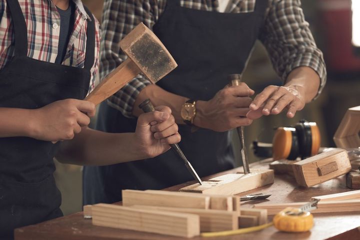 People using woodworking tools to build a wooden box at a workshop table