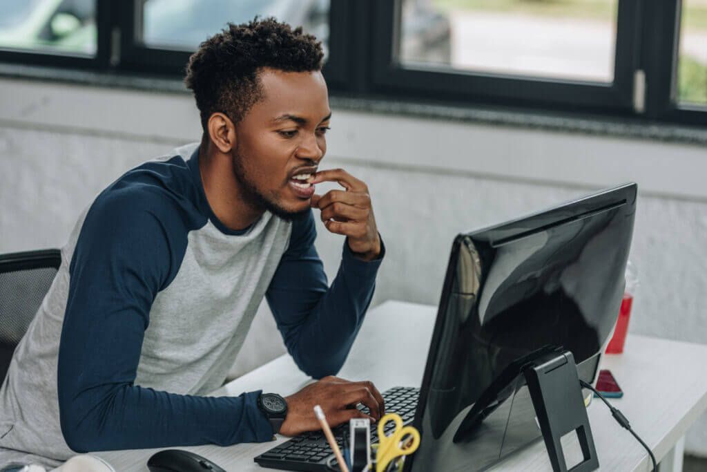 Um homem está sentado em uma mesa em frente a um computador.