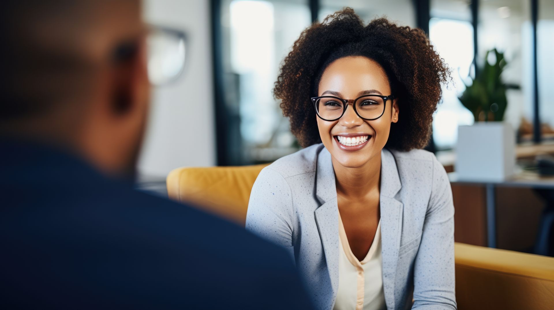 Uma mulher sorri enquanto faz uma entrevista de emprego com um homem.