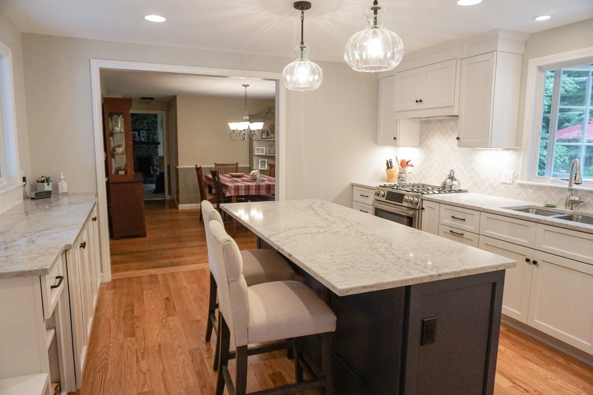 A kitchen with a large island in the middle and a dining room in the background.
