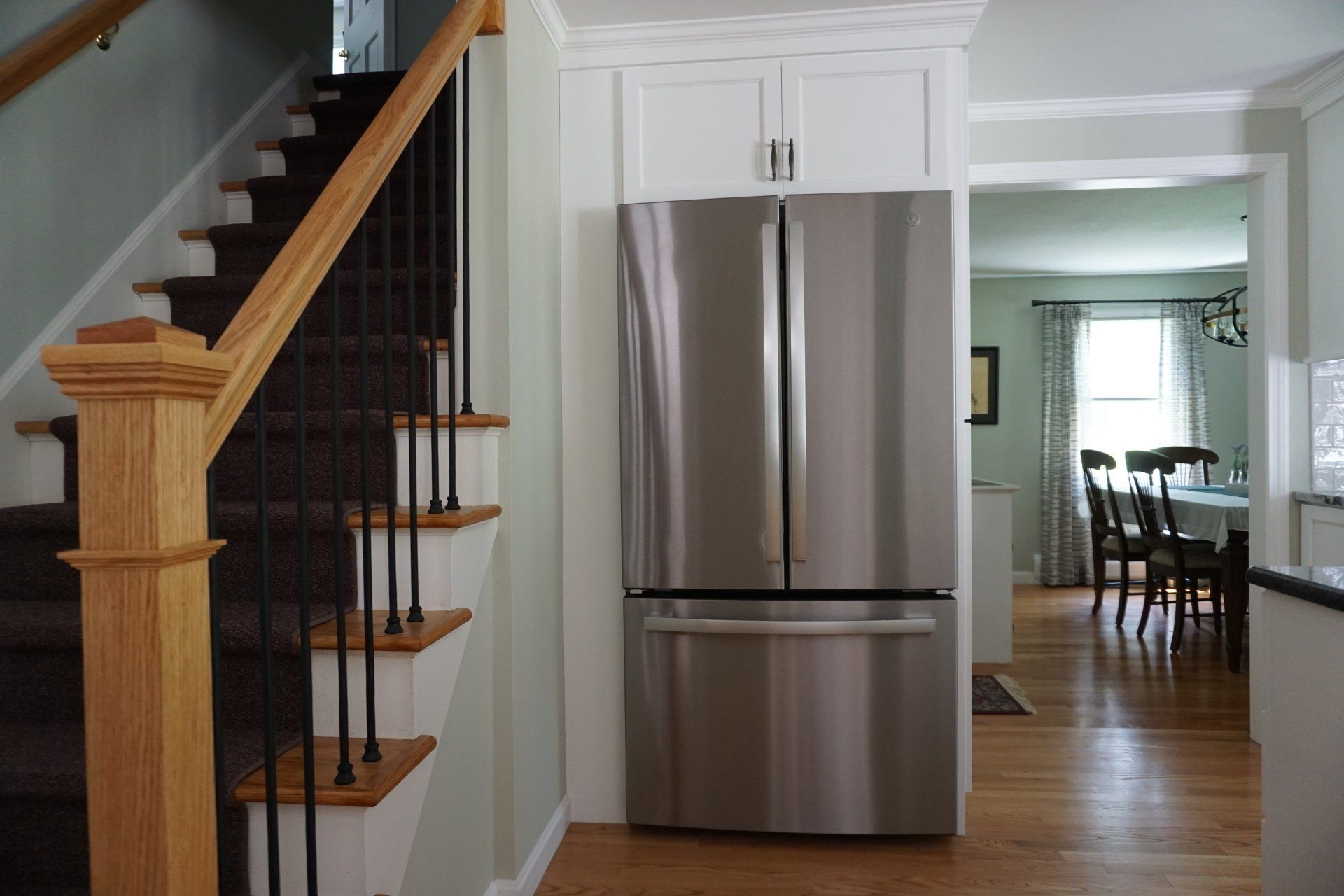 A stainless steel refrigerator in a kitchen next to stairs