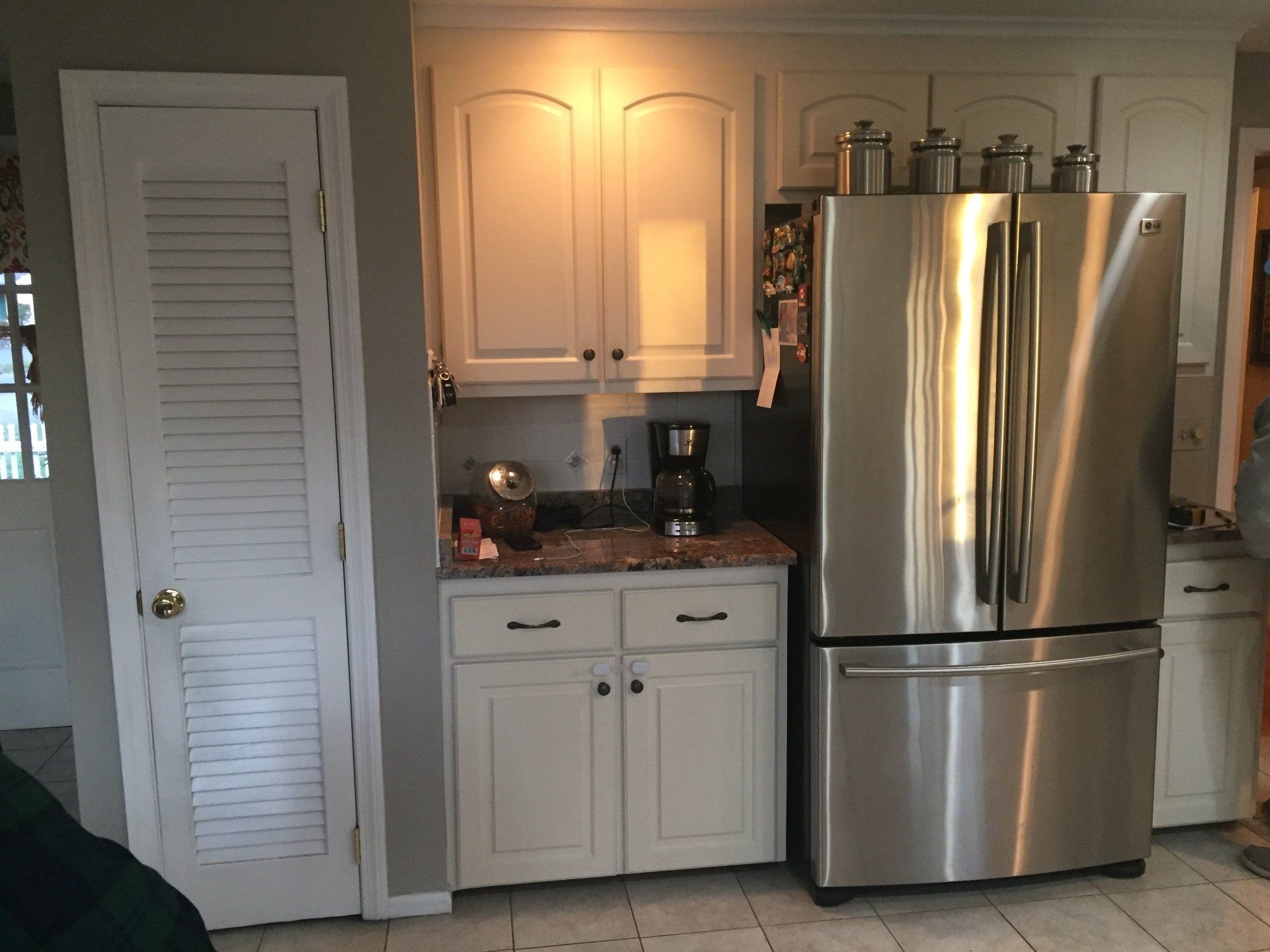 A kitchen with white cabinets and a stainless steel refrigerator