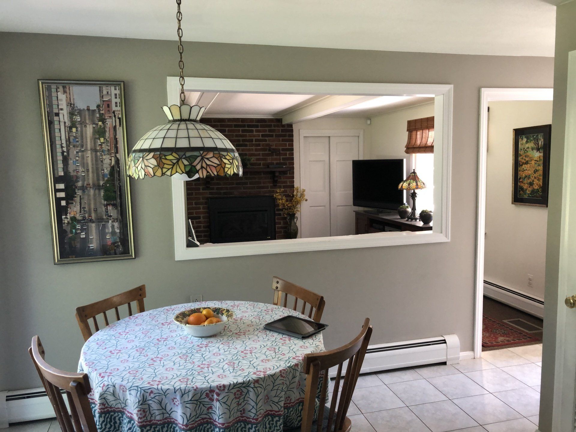 A dining room with a round table and chairs and a stained glass light fixture.