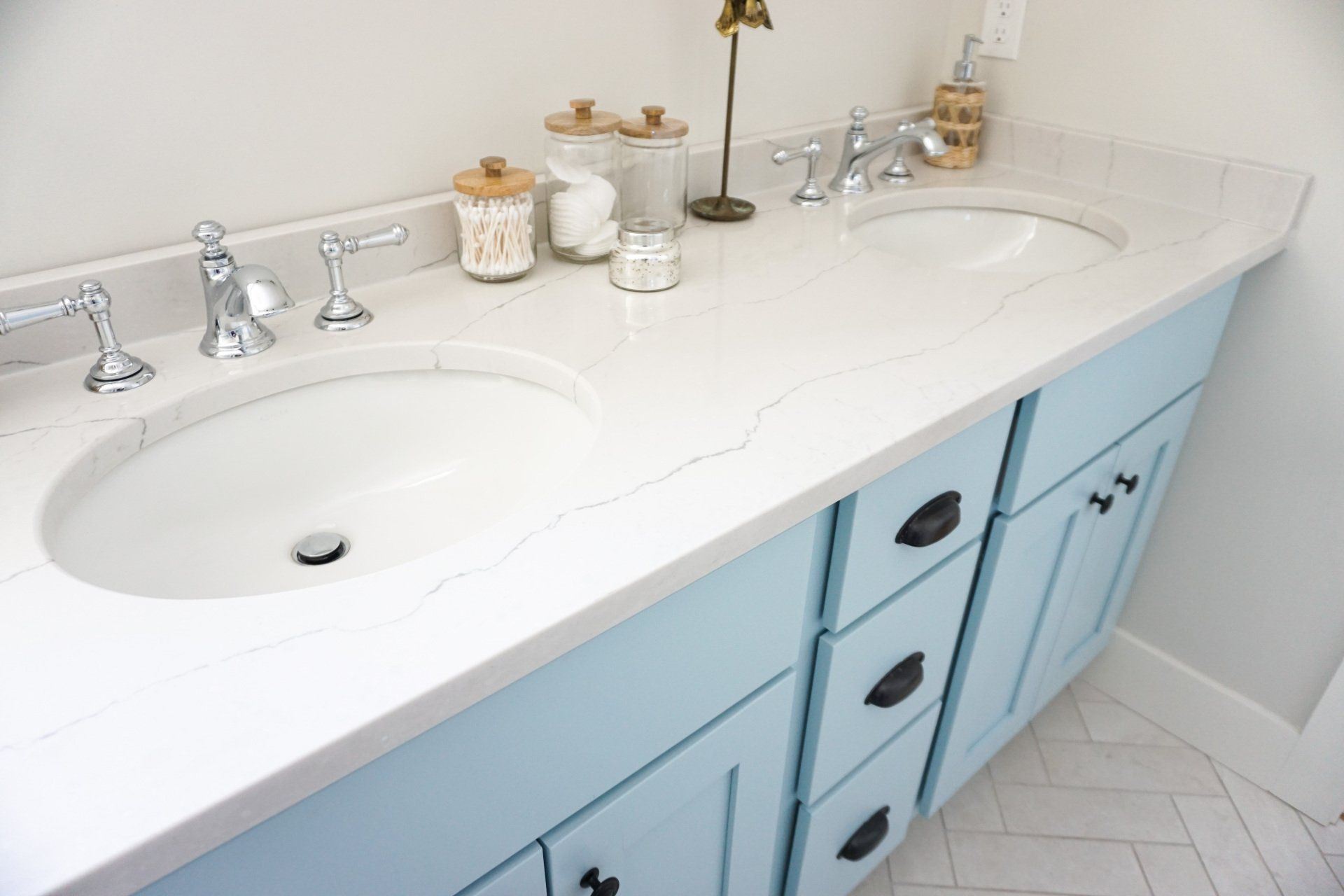 A bathroom with two sinks and blue cabinets.